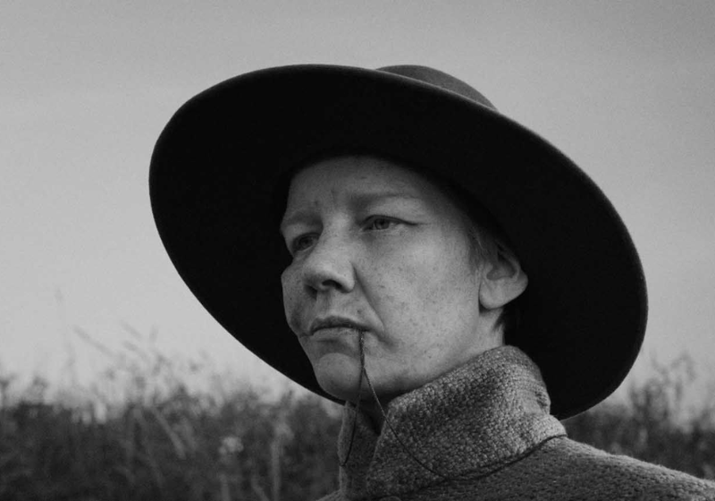 Un homme avec un chapeau dans la tête tient quelque chose dans la bouche. Photo en noir et blanc